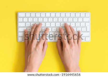 top view on female elegant hands on a computer keyboard isolated yellow background and clipping. Assistance service respond on e mail.

