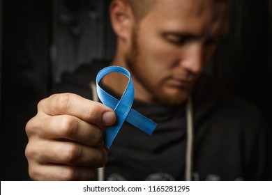 Top View On Hands Holding Prostate Cancer Ribbon, Colon Cancer Concept, Blue Ribbon Symbol