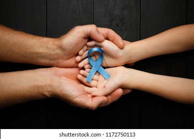 Top View On Hands Holding Prostate Cancer Ribbon, Colon Cancer Concept, Blue Ribbon Symbol