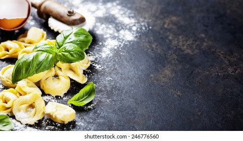 Top view on homemade tortellini with flour, tomato and basil on dark vintage background - Powered by Shutterstock