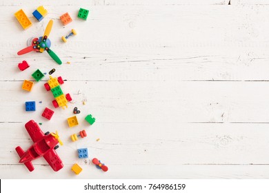 Top view on multicolor toy bricks on white wooden background. Children toys on the table. - Shutterstock ID 764986159