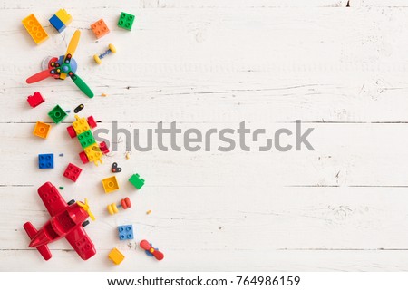 Top view on multicolor toy bricks on white wooden background. Children toys on the table.