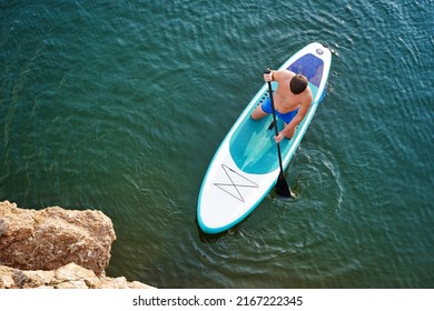 Top view on Paddleboard SUP Man having fun paddle board. Fitness recreational leisure activity. Beach rental equipment on travel vacation.