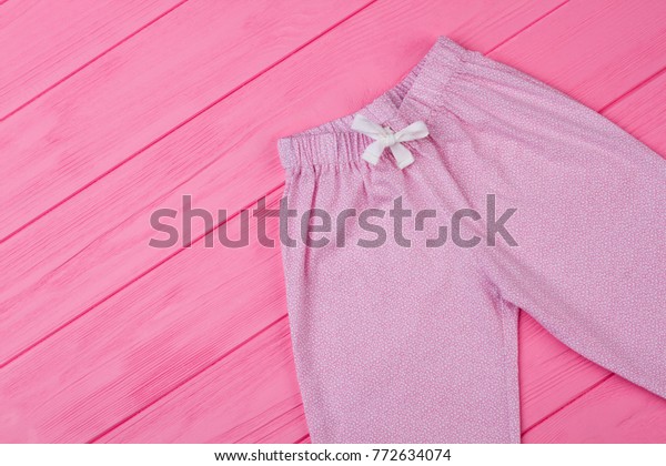 Top view\
on pajama pants. Fine pink pattern and white waist drawstring. Cute\
bottom garment for sleeping and\
lounging.