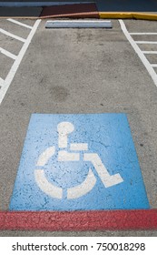 Top View On Parking Sign For Disable People. Disabled Parking Space And Wheelchair  Symbols On Asphalt.