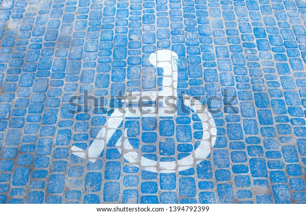 Top view on parking sign\
for disable people. Disabled parking space and wheelchair symbols\
on pavement.