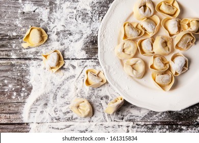 Top view on plate of homemade pasta ravioli over wooden table with flour