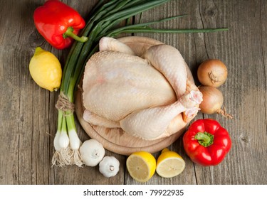 Top view on raw chicken, onion, garlic, red paprika and lemon on old wooden table - Powered by Shutterstock