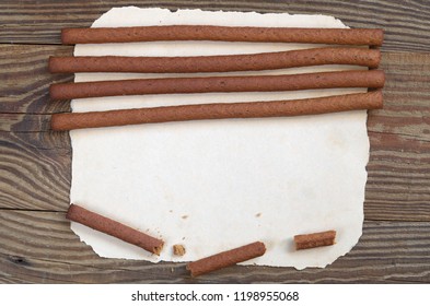 Top view on rye bread sticks on old paper, located on wooden background. Space for your text