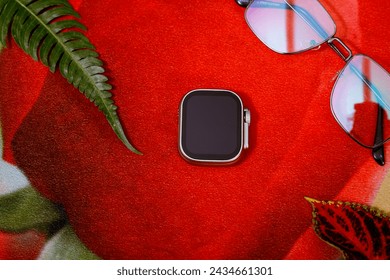 top view on Stylish smart watch and sun glass. in Red background