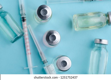 Top view on vials and syringes on blue background. Medicines for vaccination and treatment of illnesses.