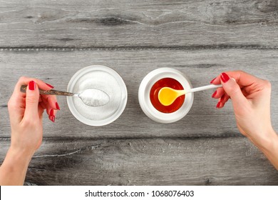 Top View On Young Woman Hands With Red Nails, Holding Spoon Full Of Sugar And Honey In Other Hand. Sugar Vs Honey Concept.