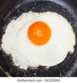 Top View Of One Fried Egg In Black Frypan Close Up