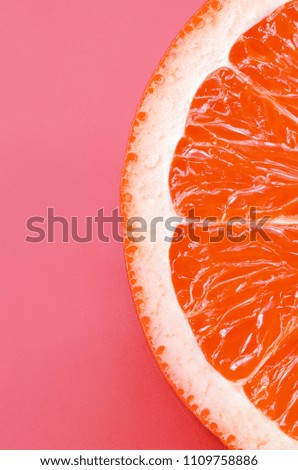 Top view of a one grapefruit slice on bright background in light pink color. A saturated citrus texture image