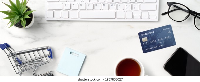 Top View Of Online Shopping Concept With Credit Card, Smart Phone And Computer Isolated On Office Marble White Table Background.