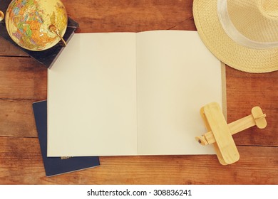 top view of open blank notebook and wooden aeroplane and wicker hat over wooden table. ready for mockup. retro filtered image 
