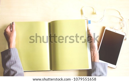 Top view of open book and tablet with space for text on soft light vintage background