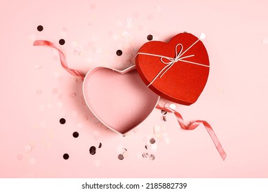 Top view of an open empty red heart shaped box on pink confetti background for your products. Happy Valentine's Day, Women's Day, Mother's Day, Birthday.