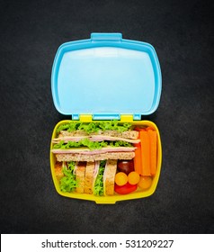 Top View Of A Open Lunch Box With Sandwich And Vegetables