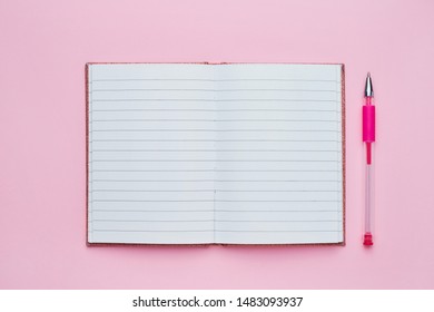 Top view of an open notebook with blank page with pink pen as mockup for your design. School notebook on a pink background. Back to school concept.