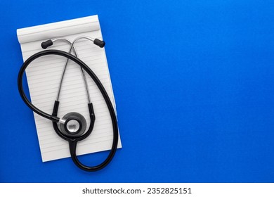 Top view of a open notebook with Medical stethoscope on a blue background, spiral office notepad flat lay. - Powered by Shutterstock