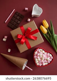 top view of an open present box with yellow color tulip flower , dark chocolate bar