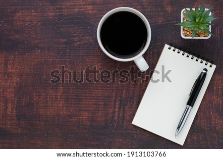 Top view of open school notebook with blank pages, coffee cup and pen for taking write notes on wood table background. Flat lay, creative workspace office. Business-education concept with copy space.