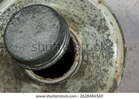 Top view of an open screw cap on an old tin bottle. The rough metal surface highlights the wear and functional charm of rugged industrial design.