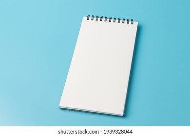 Top view of open spiral blank notebook  on blue background 