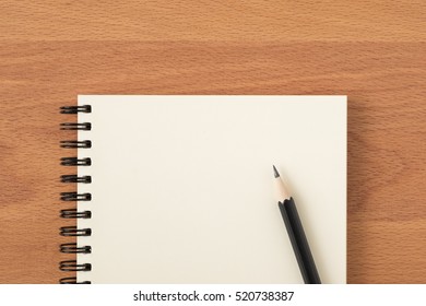 Top View Of Open Spiral Blank Notebook With Pencil On Wood Desk Background