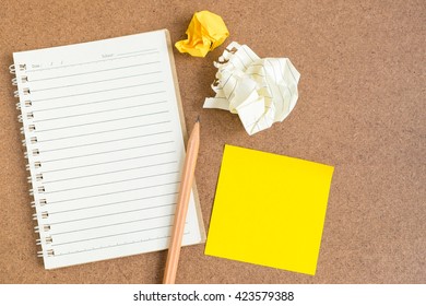 Top View Of Open Spiral Notebook, Empty Line Paper With Brown Pencil And Yellow Sticky Notes And Crumpled Paper Ball - Notebook Paper On Brown Background