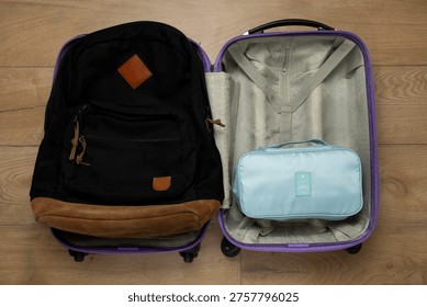 Top view of open suitcase with backpack and organizer showing travel packing concept.
