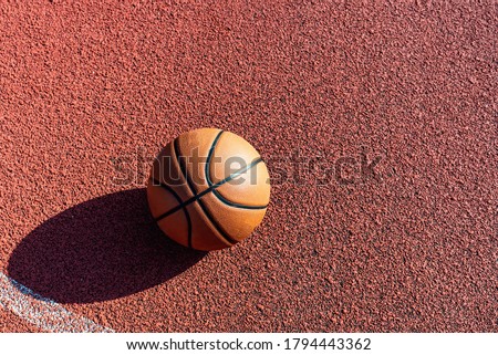 Top view orange ball for basketball lying on the rubber sport court.Sport red ground outdoor in the yard.Copy space