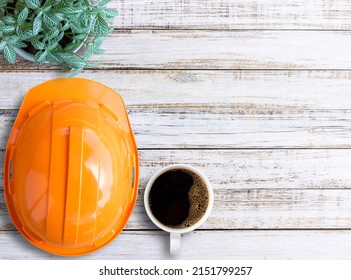 Top view with orange safety helmet and cup of coffee on wood table in office workplace. copy space for your any desing. father's day and labor day concept