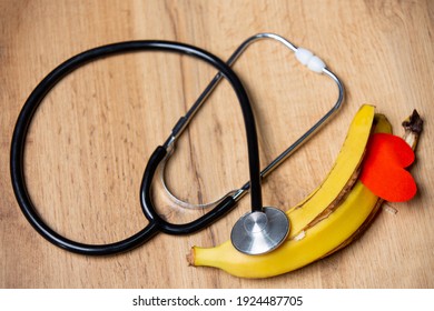 Top view. Organic,healthy food and medical concept on wooden background. Bitten banana with red paper heart shape and stethoscope for health concept. Raw vegan food, healthy life. High quality photo