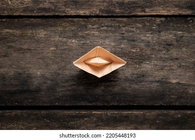 Top View Of An Origami Boat Made Of Polka Dot Paper Placed On Rustic Wooden Boards.