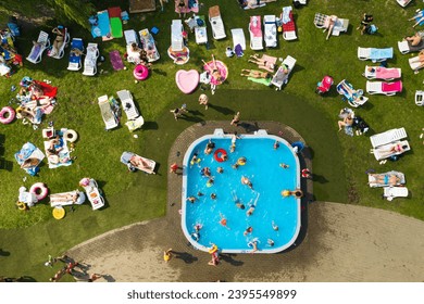 Top view of an outdoor place for people to relax where there is a swimming pool and a lot of sun beds. - Shutterstock ID 2395549899