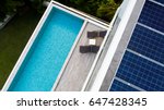 Top view of outdoor swimming pool and solar panels on the roof of villa