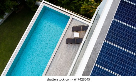 Top view of outdoor swimming pool and solar panels on the roof of villa