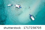 Top view of outrigger boats and swimming tourists in a submerged sandbar near Mactan Island
