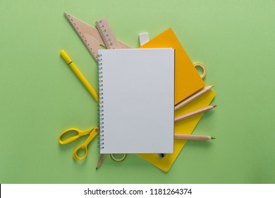 Top view over a notebooks, pencils, scissors, rulers, tapes and eraser on a green background. Back to school concept. Office supplies flat lay. - Powered by Shutterstock