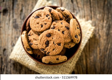 Top view and overhead shot of  chocolate chip cookies in cup bowl on  napkin with rustic wooden background - Powered by Shutterstock