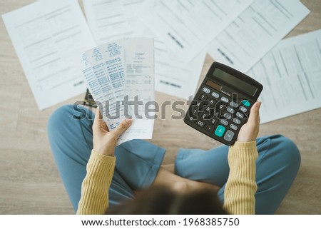 Top view owe asian woman, female sitting on floor stressed and confused by calculate expense from invoice or bill, have no money to pay, mortgage or loan. Debt, bankruptcy or bankrupt concept.