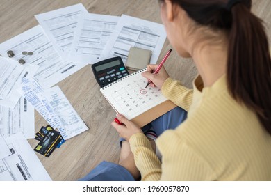 Top view owe, mortgage asian woman, female sitting on floor home, stressed calculate expense from bills, no money pay in mark circle deadline on calendar.Debt, bankruptcy or bankrupt person concept. - Shutterstock ID 1960057870