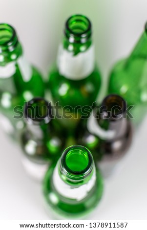 Top view of a pack of blurred  empty green and brown glass bottles, with ripped labels on a white background. Reuse, acoholism, recycle and party concept. Warm tones