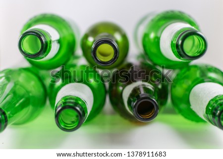 Top view of a pack of empty beer and wine green and brown glass bottles, with ripped labels on a white background. Reuse, acoholism, recycle and party concept