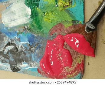 A top view of a paintbrush dipped in pink paint put on the color-mixing board - Powered by Shutterstock