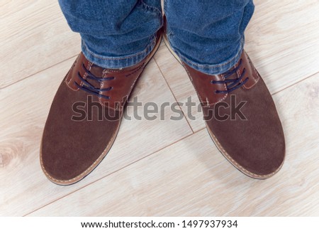Top view. Pair of male brown suede shoes on  feet on the wooden background