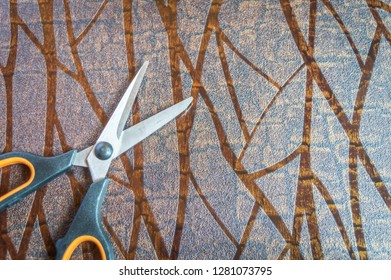 top view of a pair of scissors kept on a textured brown table. Copy space provided