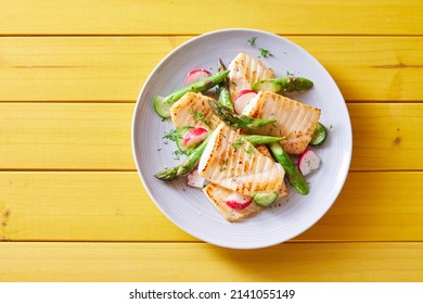 Top view of palatable grilled tilapia fish with cut vegetables served on plate on wooden table - Shutterstock ID 2141055149